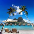 Two beach chairs and solar umbrella under a palm tree and a view of the sea and mountains. Tahiti Royalty Free Stock Photo