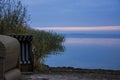 Two beach chairs stand abandoned on a vegetated bank.