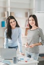 Two beaming dark-haired woman spending time in workspace