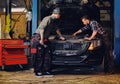 Two mechanics fixing car`s engine in a garage. Royalty Free Stock Photo