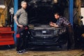 Two mechanics fixing car`s engine in a garage. Royalty Free Stock Photo