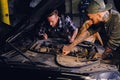 Two mechanics fixing car`s engine in a garage. Royalty Free Stock Photo