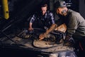 Two mechanics fixing car`s engine in a garage. Royalty Free Stock Photo