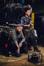 Two bearded tattooed mechanics near the car in a workshop. Royalty Free Stock Photo