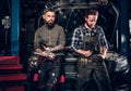 Two bearded tattooed mechanics near the car in a workshop. Royalty Free Stock Photo