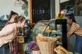 Two beautiful Asian female customers, walk into cafe head straight for bakery cake cabinet with lots sweets, beautiful shop owner