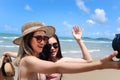 Two beautiful Asian women with big hat and sunglasses enjoy spending time with friend on tropical sand beach blue sea together, ta Royalty Free Stock Photo