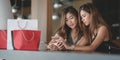 Two beautiful asian women checking their smartphone and chatting together