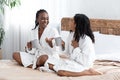 Two beautiful black girlfriends drinking tea in bedroom Royalty Free Stock Photo