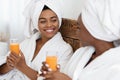 Two beautiful black women drinking fresh juice in bed