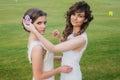 Two beautiful brides correcting hair on the green field