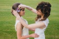 Two beautiful brides correcting hair on the green field