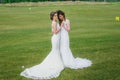 Two beautiful brides dancing on the green field