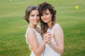 Two beautiful brides dancing on the green field