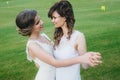 Two beautiful brides dancing on the green field