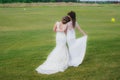 Two beautiful brides embracing on the green field