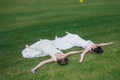 Two beautiful brides lying on the green field Royalty Free Stock Photo