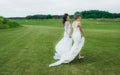 Two beautiful brides walking on the green field