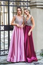 Two beautiful bridesmaids girls blonde and brunette ladies wearing elegant full length purple violet lilac lavender