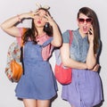 Two beautiful brunette women (girls) teenagers spend time together having fun, make funny faces. Jeans dresses outfit Royalty Free Stock Photo