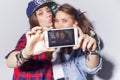 Two beautiful brunette women (girls) teenagers spend time together having fun, make funny faces, making selfie. Casual hipster Royalty Free Stock Photo