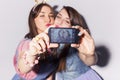 Two beautiful brunette women (girls) teenagers spend time together having fun, make funny faces, making selfie. Jeans dresses out Royalty Free Stock Photo