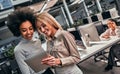 Two beautiful business women looking at a tablet at work in the office. Teamwork. The concept of business, management, training,