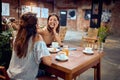 Two beautiful cheerful women having coffee in restaurant, talking and laughing Royalty Free Stock Photo