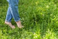 Two beautiful female feet walking on grass in sunny summer morning. Light step barefoot girl legs on soft spring lawn in garden or Royalty Free Stock Photo