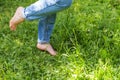 Two beautiful female feet walking on grass in sunny summer morning. Light step barefoot girl legs on soft spring lawn in garden or Royalty Free Stock Photo