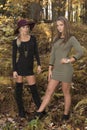 Two beautiful female friends pose in dresses in autumn woods - fashion