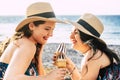 Two beautiful female friends in straw hat having fun enjoying cold ice cream cones on a peaceful beach during summer holiday. Royalty Free Stock Photo