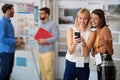 Two beautiful female looking at cell phone with two handsome men in background. friends, business partners, communication concept Royalty Free Stock Photo