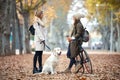 Two beautiful friends talking while walking with their dog and bike in the park in autumn Royalty Free Stock Photo