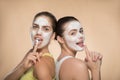 Two beautiful girls applying facial cream mask and