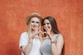 Two beautiful girls brunette and blonde, students, sisters, girlfriends walk . Smiling women, positive emotions show the heart Royalty Free Stock Photo