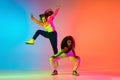 Two beautiful girls dancing hip-hop on colorful gradient background in neon lights Royalty Free Stock Photo