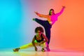 Two beautiful girls dancing hip-hop on colorful gradient background in neon lights Royalty Free Stock Photo