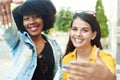 Two beautiful girls of different nationalities show the photo frame with their hands and smile at the camera. Young Royalty Free Stock Photo