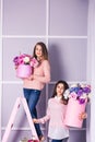 Two beautiful girls in jeans and pink sweater in studio with decor of flowers in baskets. Royalty Free Stock Photo