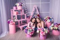 Two beautiful girls in jeans and pink sweater in studio with decor of flowers in baskets. Royalty Free Stock Photo