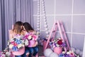 Two beautiful girls in jeans and pink sweater in studio with decor of flowers in baskets. Royalty Free Stock Photo