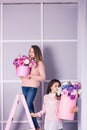 Two beautiful girls in jeans and pink sweater in studio with decor of flowers in baskets. Royalty Free Stock Photo