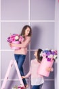 Two beautiful girls in jeans and pink sweater in studio with decor of flowers in baskets. Royalty Free Stock Photo