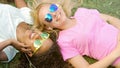 Two beautiful girls listening to music on smartphone, lying on grass on campus Royalty Free Stock Photo