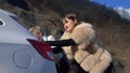 Two beautiful girls push the broken car on the road. a man sits behind the wheel