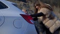 Two beautiful girls push the broken car on the road. a man sits behind the wheel