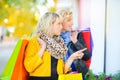 Two girls with shopping bags are standing at the shop window Royalty Free Stock Photo