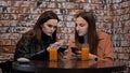 Two beautiful girls are sitting in a cafe and talking with phones. Royalty Free Stock Photo