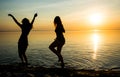 Two beautiful girls are dancing on the beach at sunset background, silhouettes Royalty Free Stock Photo